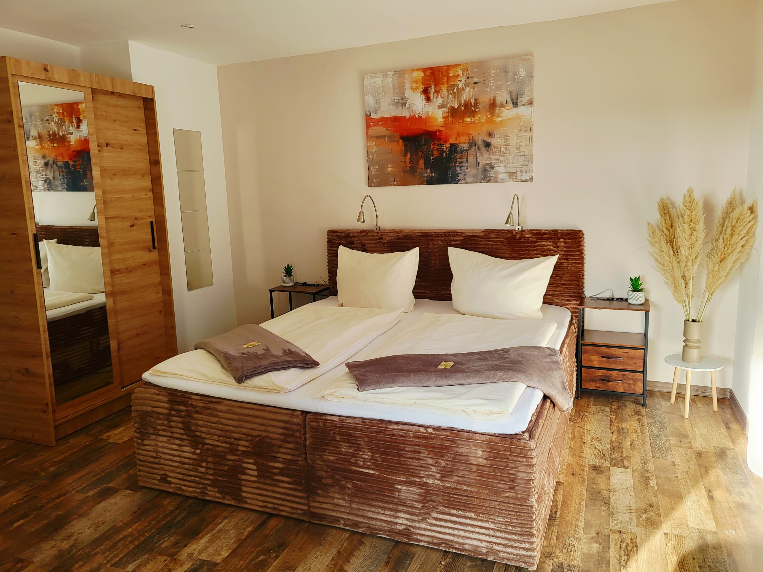 gemütliches Doppelbett mit Nachttisch und Leselampen im Apartment Adenauer Forst, Apartments am Nürburgring